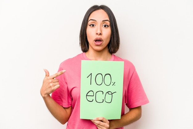 Young hispanic woman holding 100 eco placard isolated on white background pointing to the side