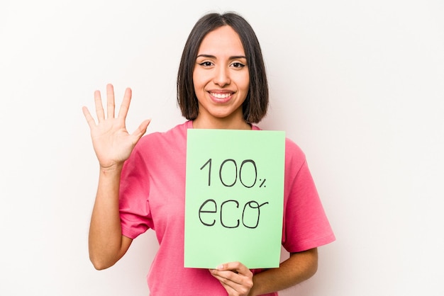 Young hispanic woman holding 100 eco placard isolated on white background smiling cheerful showing number five with fingers