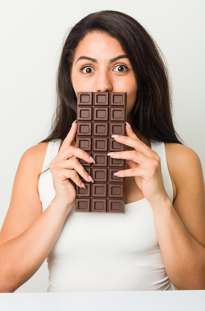 Молодая латиноамериканская женщина, держащая шоколадную таблетку