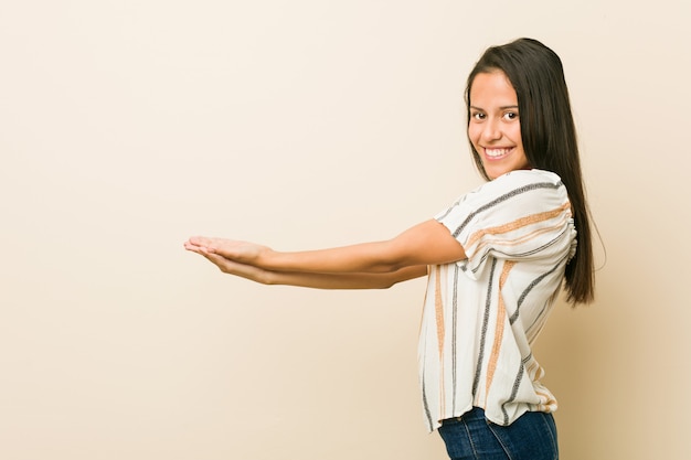 Young hispanic woman holding a copy space on a palm.