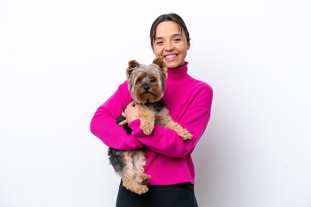 Young hispanic woman holding a dog isolated on white background smiling a lot