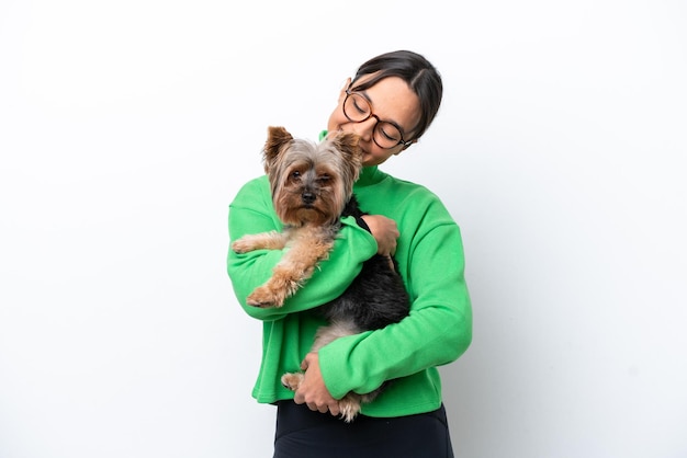 幸せな表情で白い背景に孤立した犬を抱いた若いヒスパニック系女性