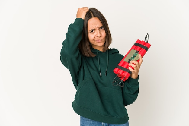 Young hispanic woman holding dynamite being shocked, she has remembered important meeting.