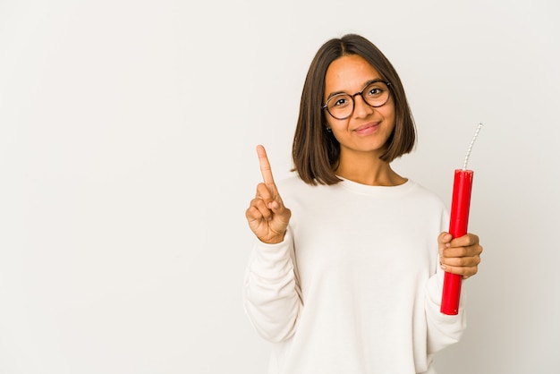 Young hispanic woman holding a dynamite showing number one with finger