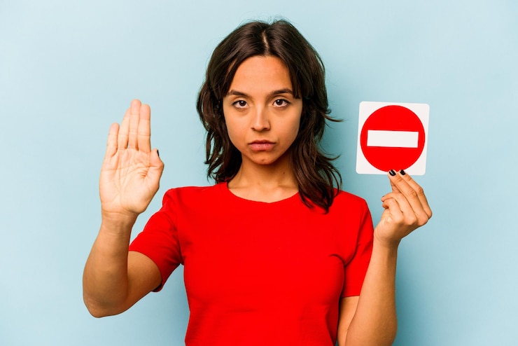 Photo young hispanic woman holding a forbidden sign isolated on blue background
