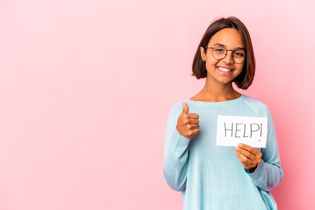 Young hispanic woman holding a help poster smiling and raising thumb up