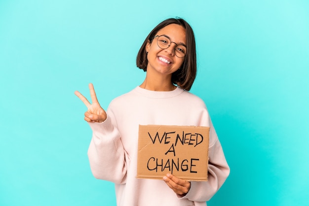 Young hispanic woman holding an inspiring change message on cardboard showing number two with fingers