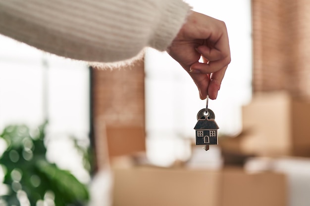 Young hispanic woman holding key of new house at new home