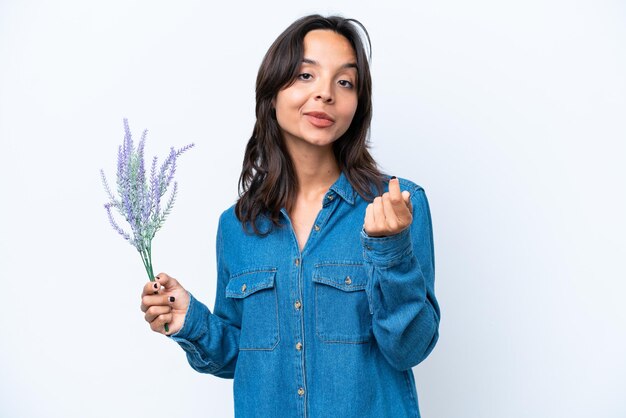 Young hispanic woman holding lavender isolated on white background making money gesture