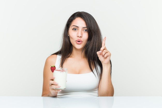 Young hispanic woman holding a smoothie young hispanic woman holding an avocado toast having some great idea, concept of creativity.< mixto >