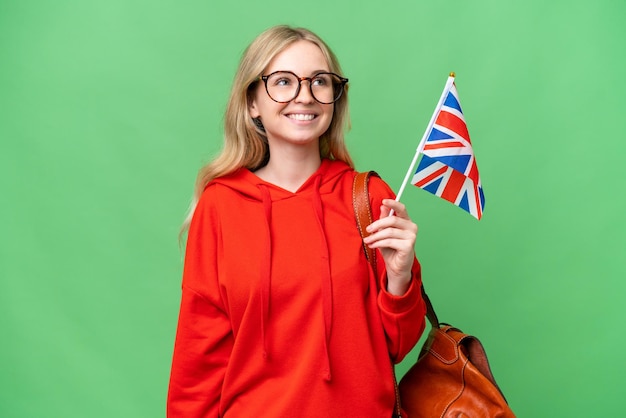 Young hispanic woman holding an united kingdom flag over isolated background thinking an idea while looking up