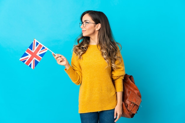 Young hispanic woman holding an United Kingdom flag isolated looking to the side