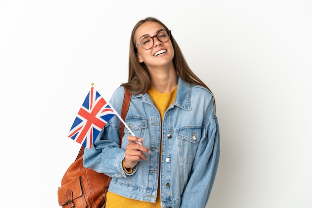 Young hispanic woman holding an United Kingdom flag over isolated white wall laughing