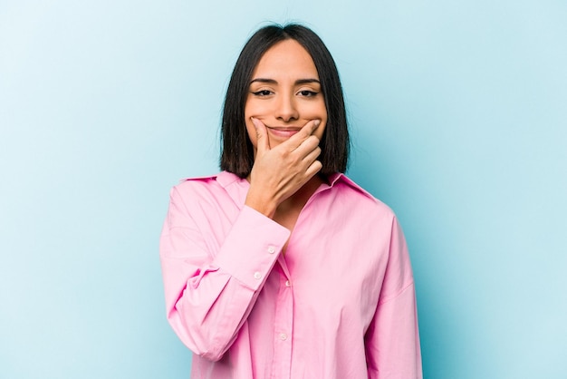 Young hispanic woman isolated on blue background doubting between two options