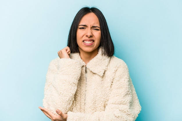 Young hispanic woman isolated on blue background massaging elbow suffering after a bad movement