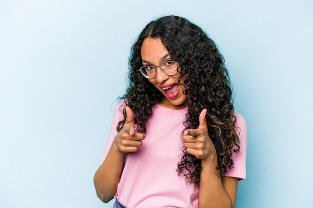 Young hispanic woman isolated on blue background pointing to front with fingers