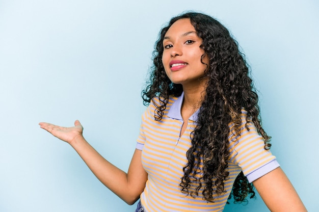 Young hispanic woman isolated on blue background showing a welcome expression