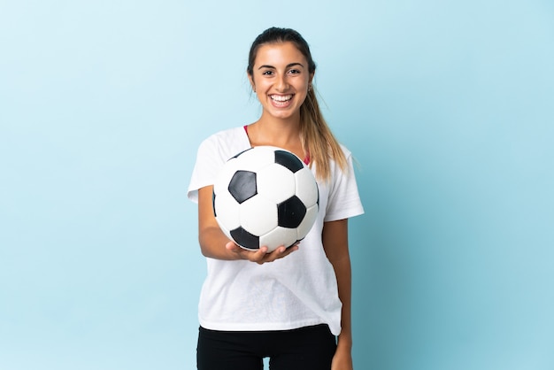 Young hispanic woman over isolated blue background with soccer ball