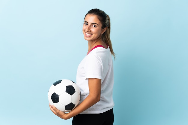 Young hispanic woman over isolated blue wall with soccer ball