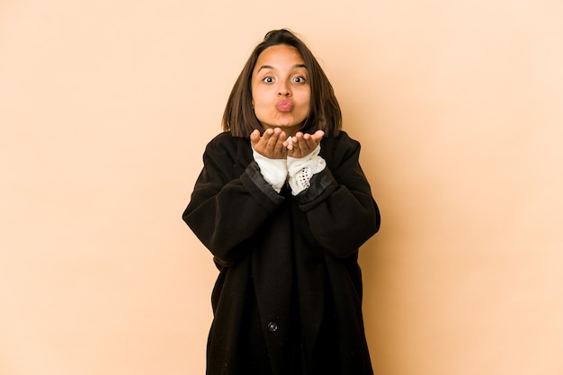 Young hispanic woman isolated folding lips and holding palms to send air kiss.