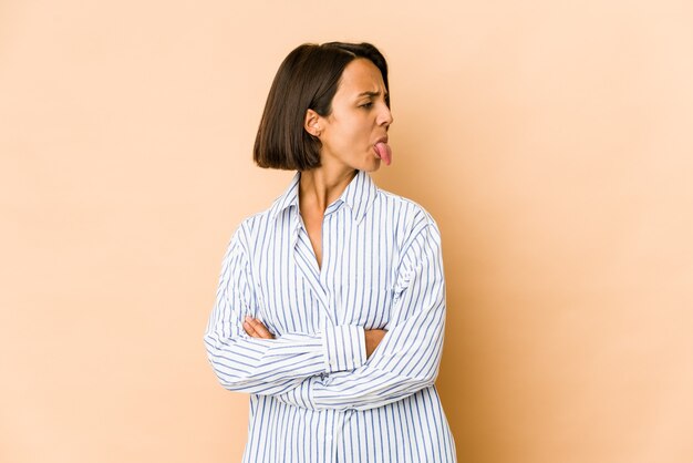 Young hispanic woman isolated funny and friendly sticking out tongue.