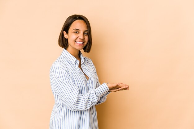 Young hispanic woman isolated holding a copy space on a palm.