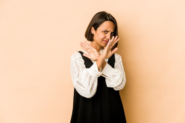 Giovane donna ispanica isolata mantenendo due braccia incrociate, concetto di rifiuto.