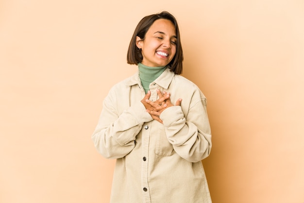 Young hispanic woman isolated laughing keeping hands on heart, concept of happiness.