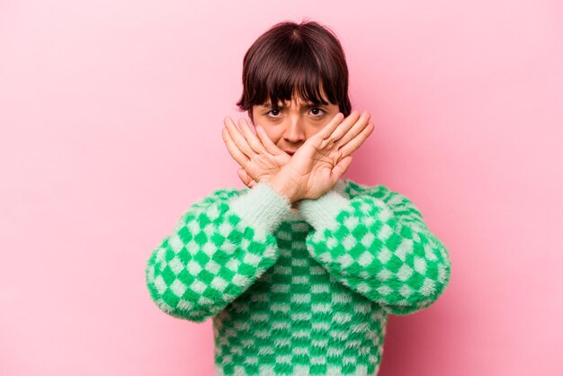 Young hispanic woman isolated on pink background doing a denial gesture