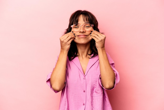 Young hispanic woman isolated on pink background doubting between two options