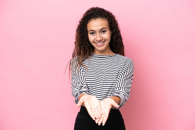 Young hispanic woman isolated on pink background holding copyspace imaginary on the palm to insert an ad