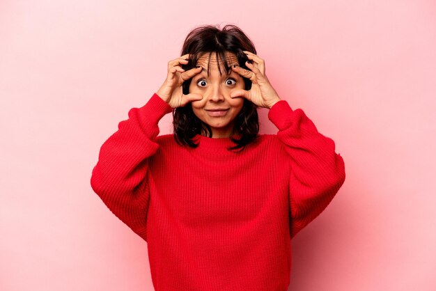 Young hispanic woman isolated on pink background keeping eyes opened to find a success opportunity