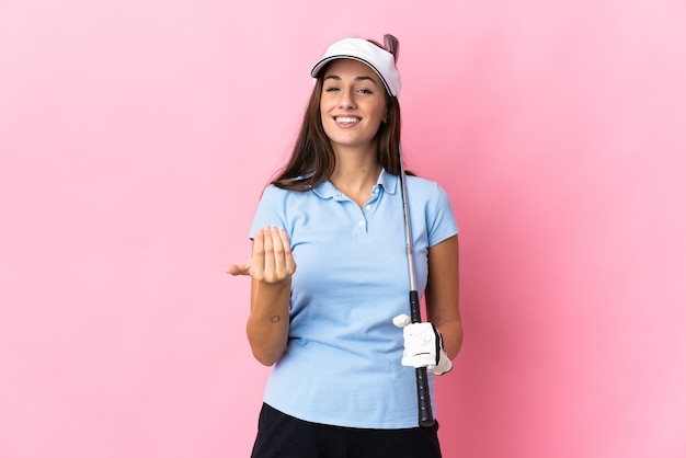 Photo young hispanic woman over isolated pink background playing golf and doing coming gesture