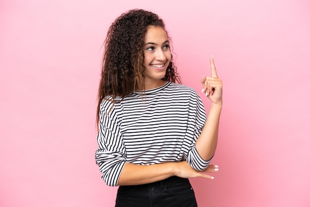 Young hispanic woman isolated on pink background pointing up a great idea