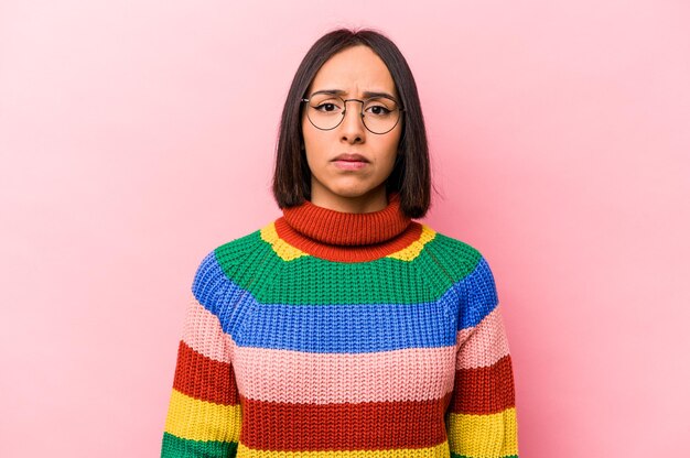 Young hispanic woman isolated on pink background sad serious face feeling miserable and displeased