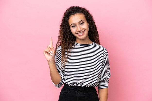 Young hispanic woman isolated on pink background showing and lifting a finger in sign of the best