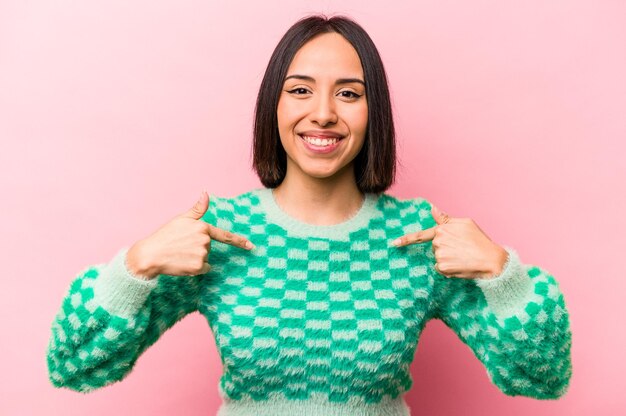 Young hispanic woman isolated on pink background surprised pointing with finger smiling broadly