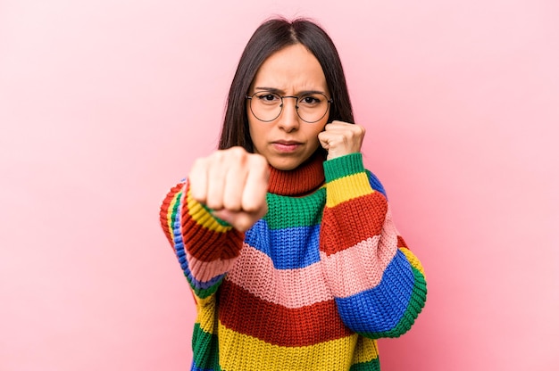 Young hispanic woman isolated on pink background throwing a\
punch anger fighting due to an argument boxing