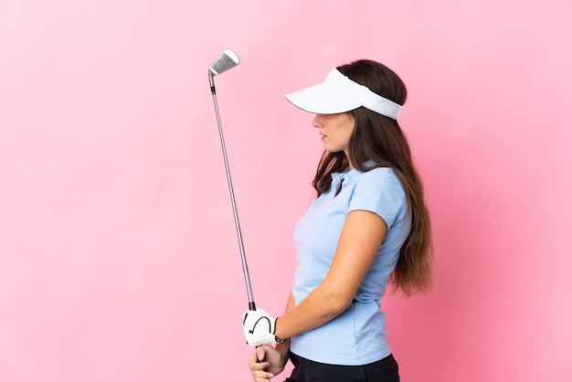 Young hispanic woman over isolated pink playing golf