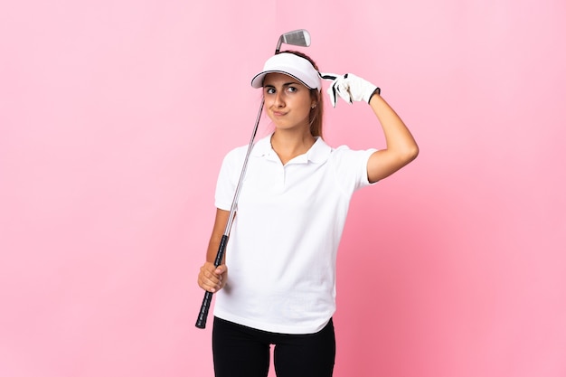 Young hispanic woman over isolated pink wall playing golf and\
and having doubts confuse face expression