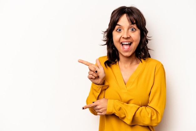 Young hispanic woman isolated on white background excited pointing with forefingers away