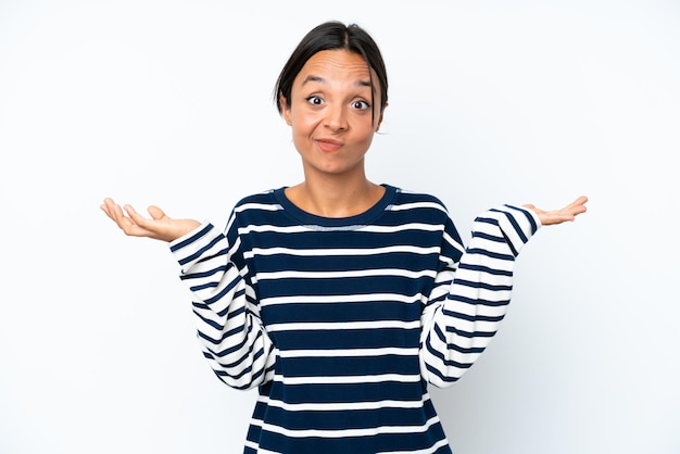 Young hispanic woman isolated on white background having doubts while raising hands