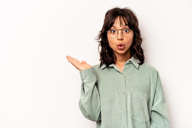 Young hispanic woman isolated on white background impressed holding copy space on palm