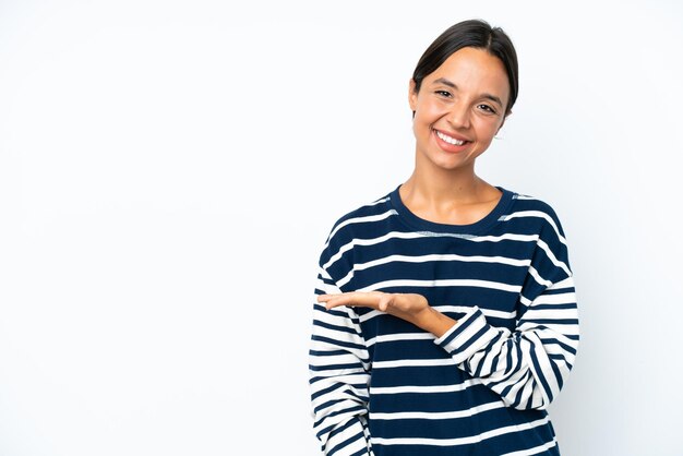 Foto giovane donna ispanica isolata su uno sfondo bianco che presenta un'idea mentre guarda sorridendo verso