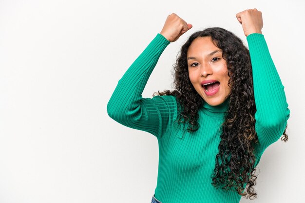 勝利の勝者の概念の後に拳を上げる白い背景で隔離の若いヒスパニック系女性