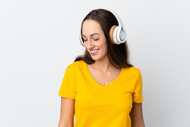 Young hispanic woman over isolated white listening music