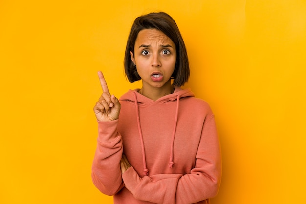 Young hispanic woman isolated on yellow having some great idea, concept of creativity