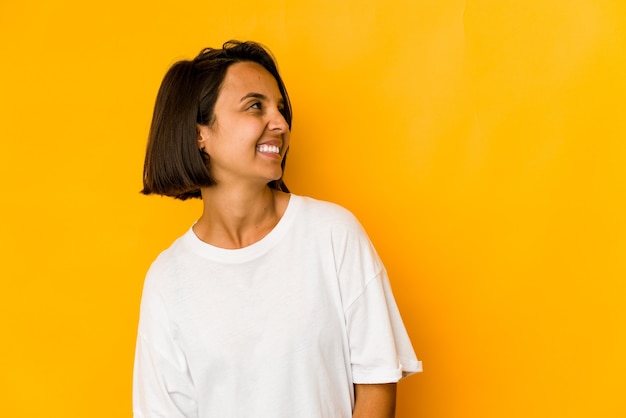 Young hispanic woman isolated on yellow relaxed and happy laughing, neck stretched showing teeth