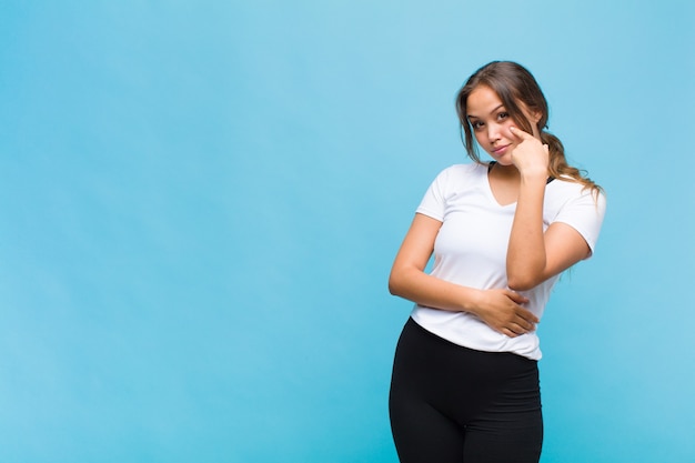 Young hispanic woman keeping an eye on you, not trusting, watching and staying alert and vigilant