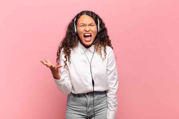 young hispanic woman looking angry, annoyed and frustrated screaming wtf or what’s wrong with you. telemarketer concept